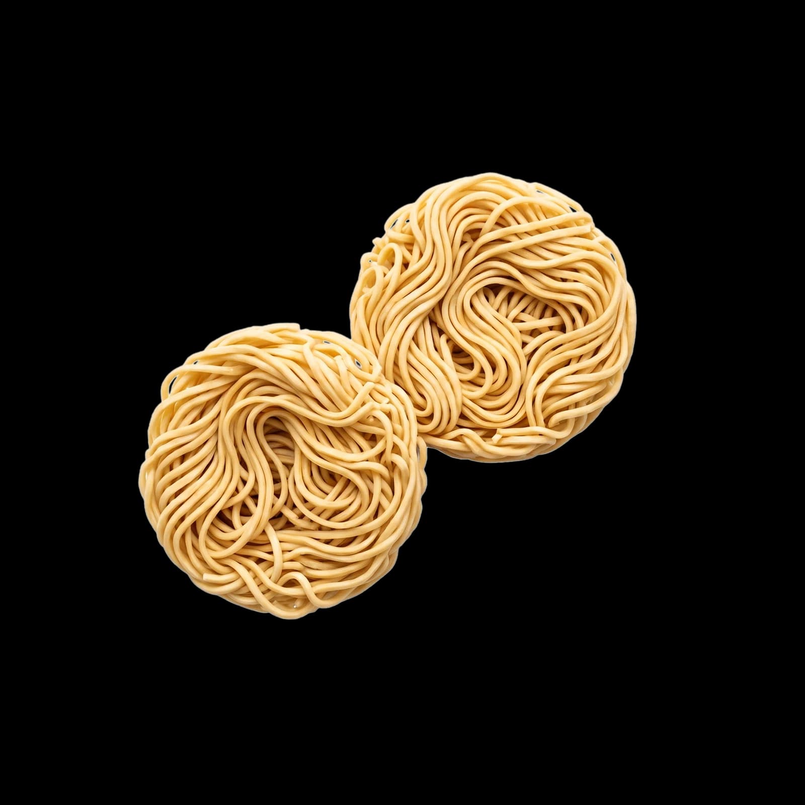 Two nests of dry wheat ramen noodles, showing the wave of the strand.