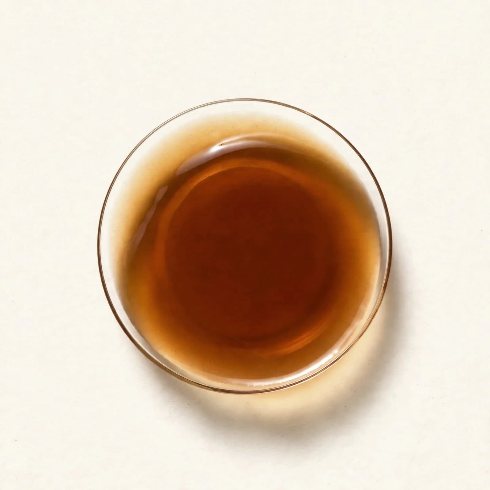 Dark amber coconut aminos in a small glass dish, seen from above.