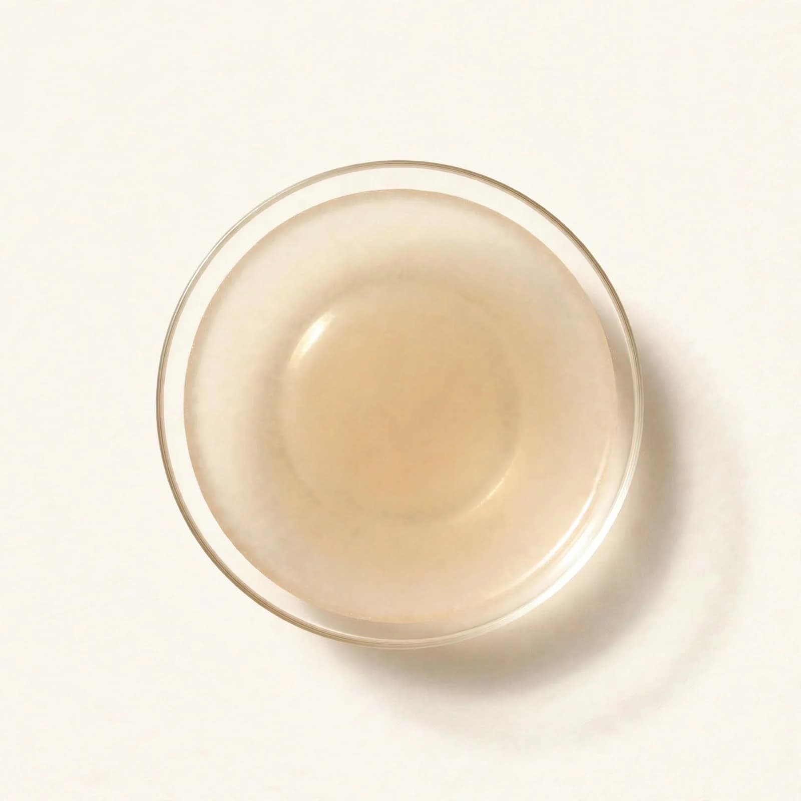 Cloudy pale coconut vinegar in a shallow glass dish, seen from above.