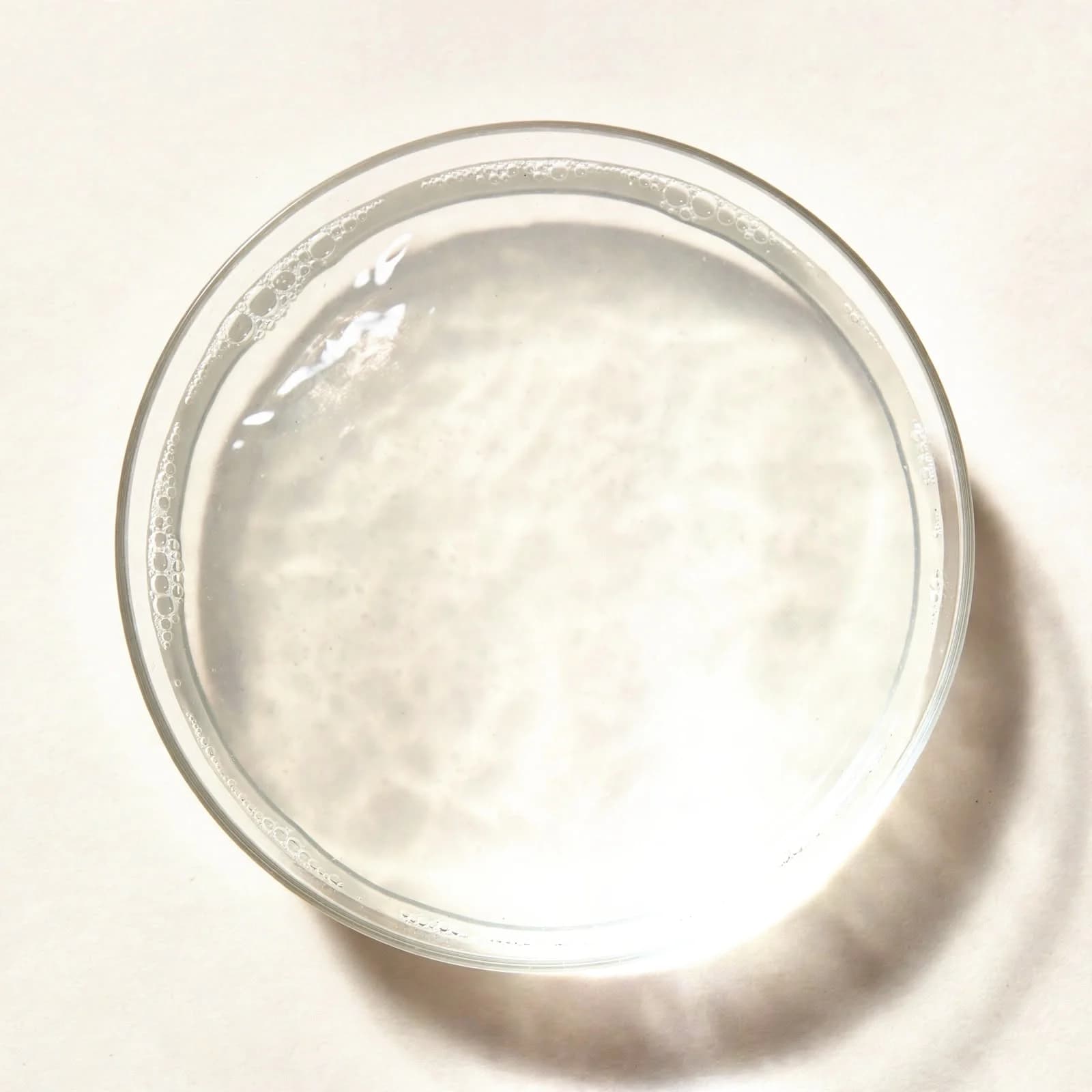 Clear coconut water in a shallow glass dish, seen from above.