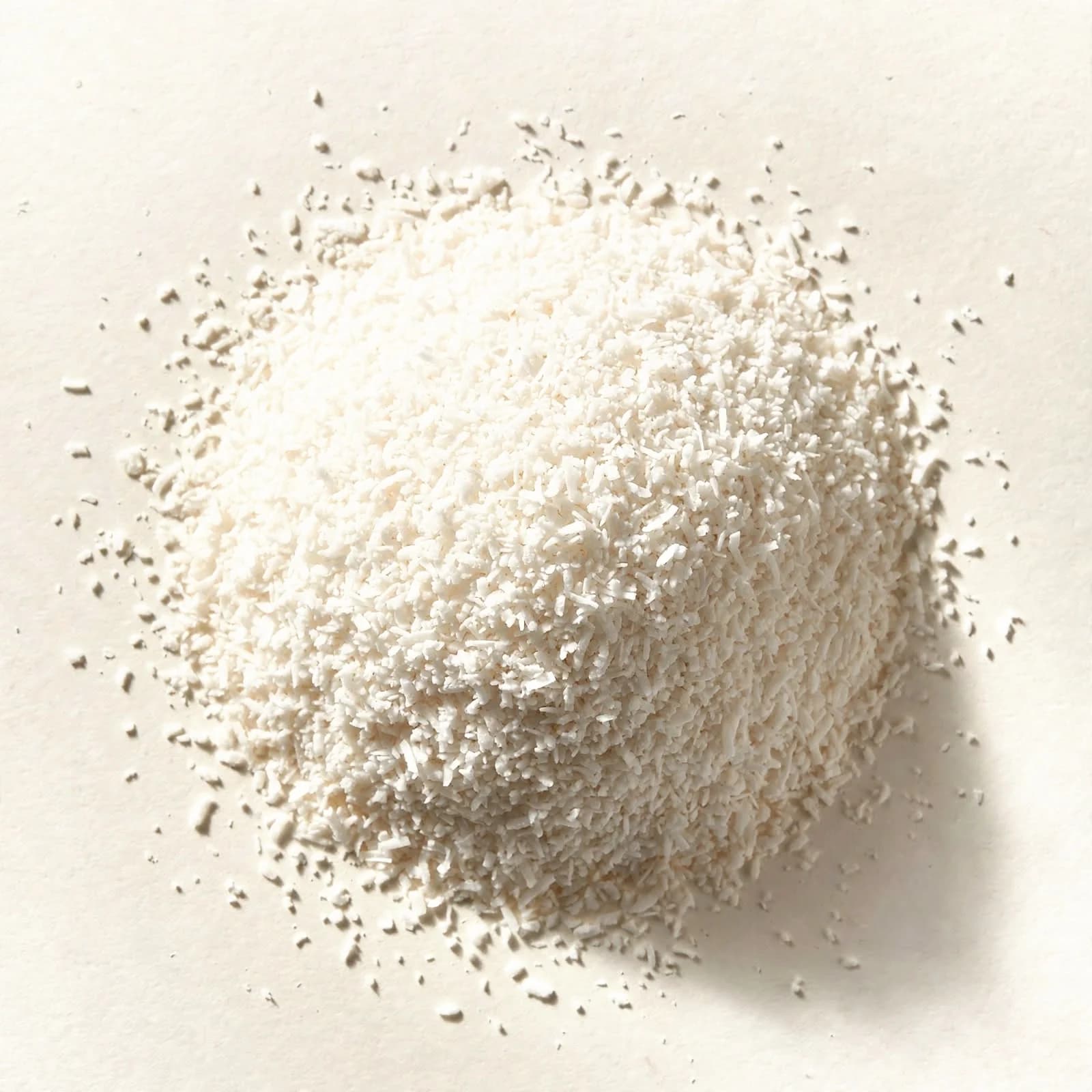 A heap of fine white desiccated coconut, seen from above.