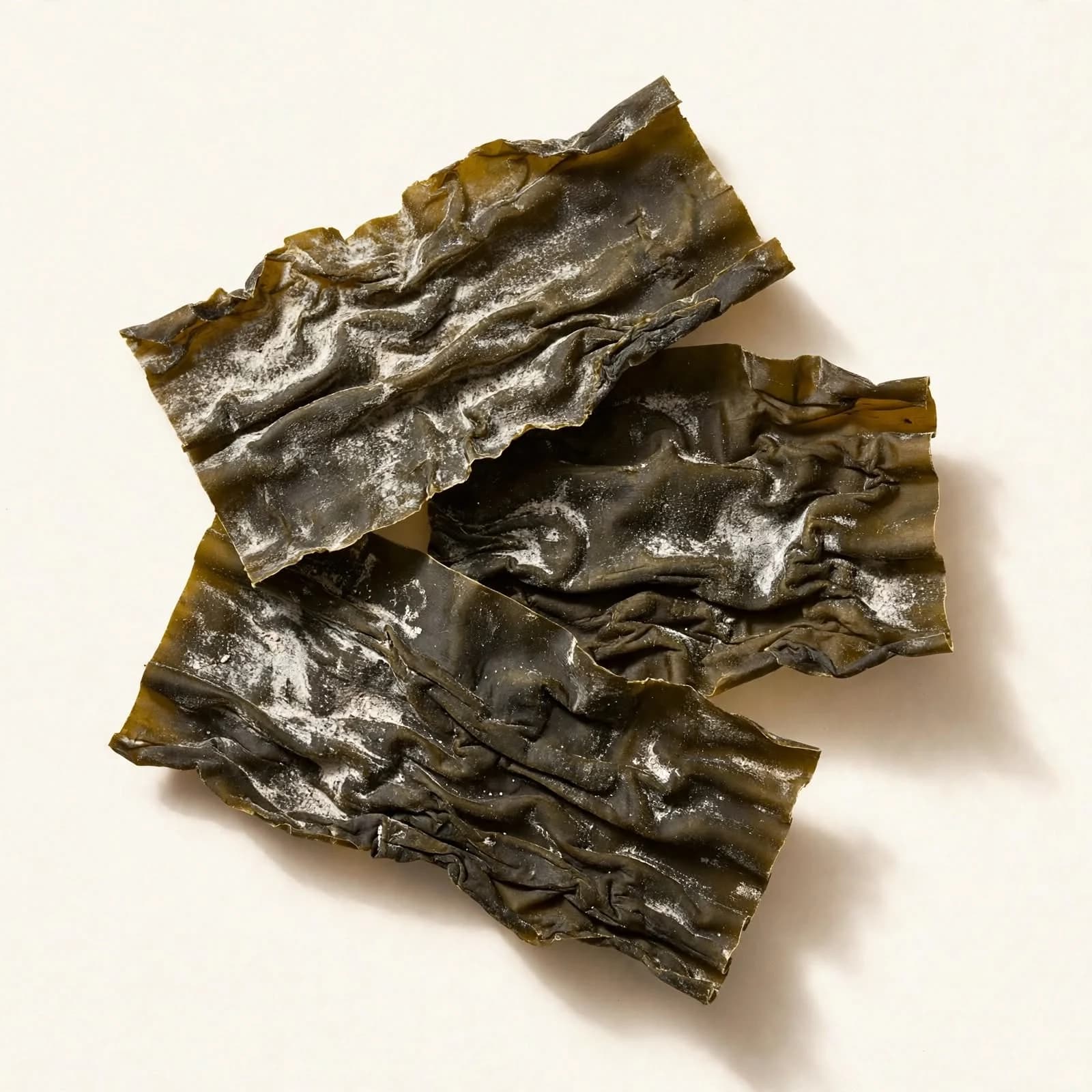 Three wide pieces of dried kombu with a wrinkled surface, seen from above.