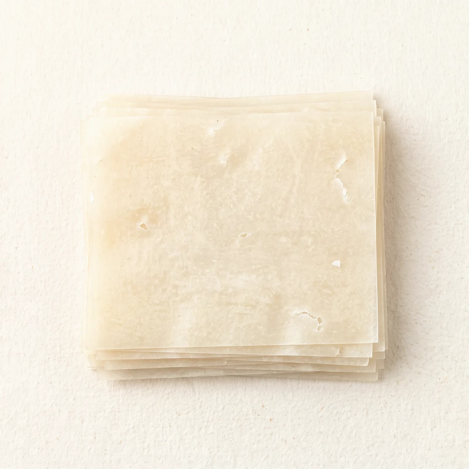 Dry rice noodle sticks, showing the translucent white color and the flat narrow cut.
