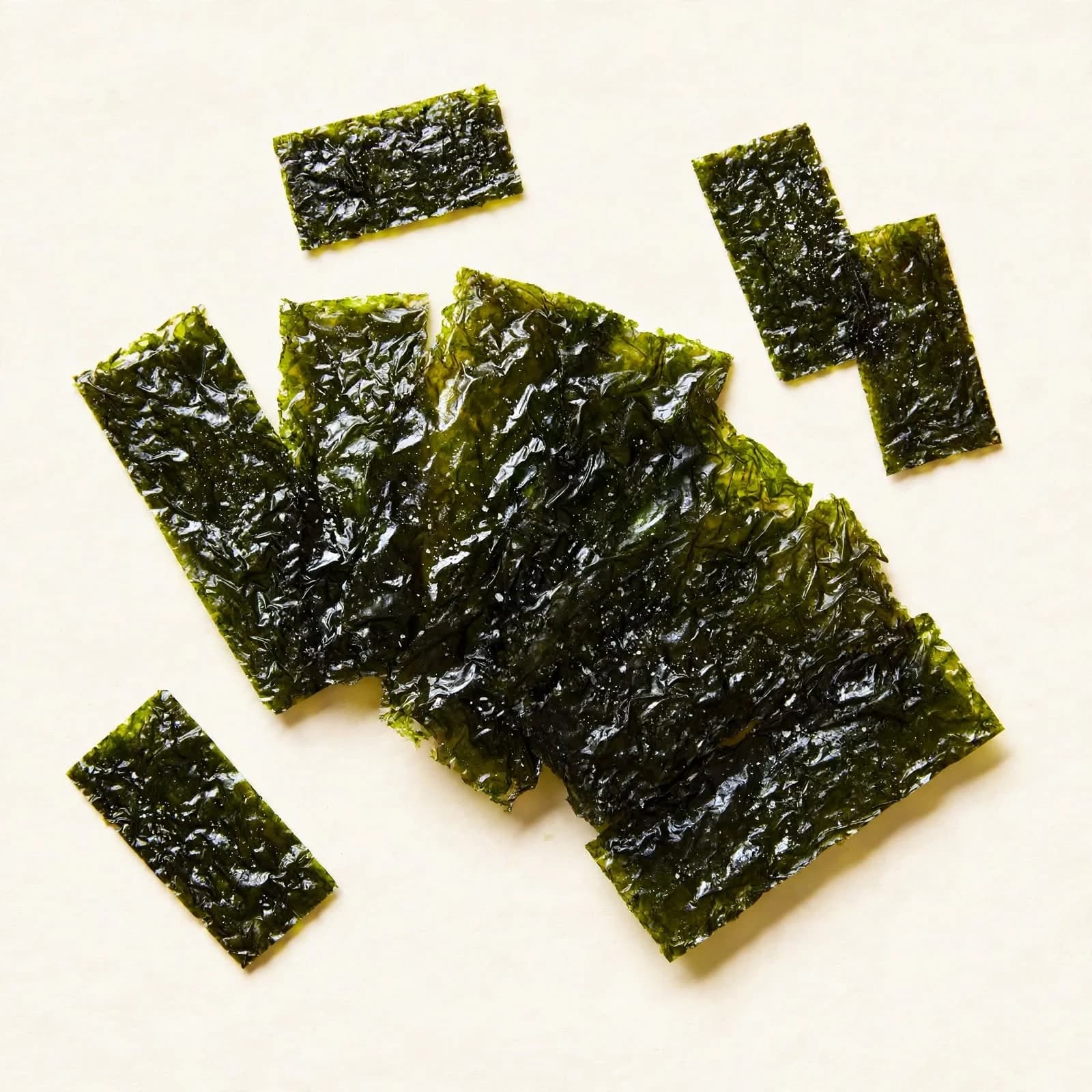 Small rectangles of roasted, seasoned seaweed scattered in a pile, seen from above.